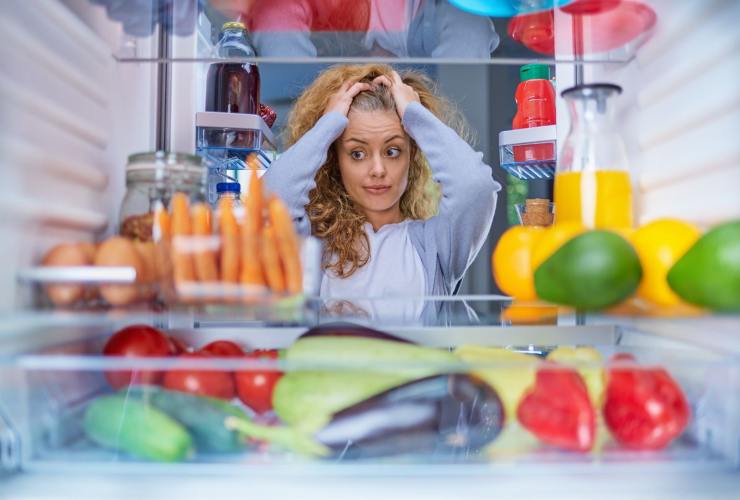 Frigo disordinato donna con le mani tra i capelli