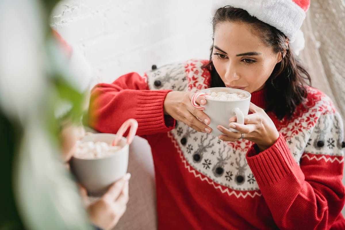 Donna vestita da Babbo Natale che beve cioccolata calda