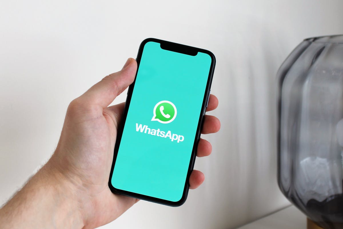 Mano che regge cellulare con schermata WhatsApp