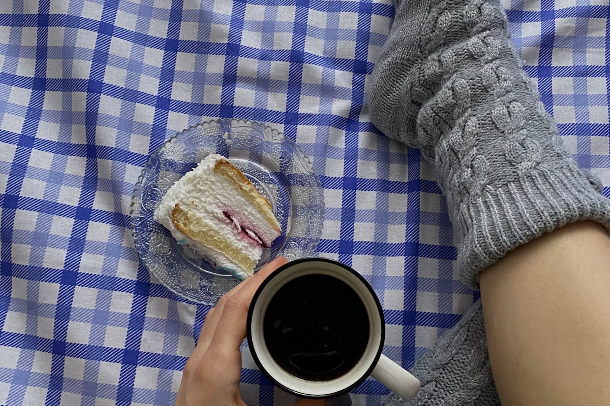 Persona che indossa calze in lana, beve cioccolata e mangia torta