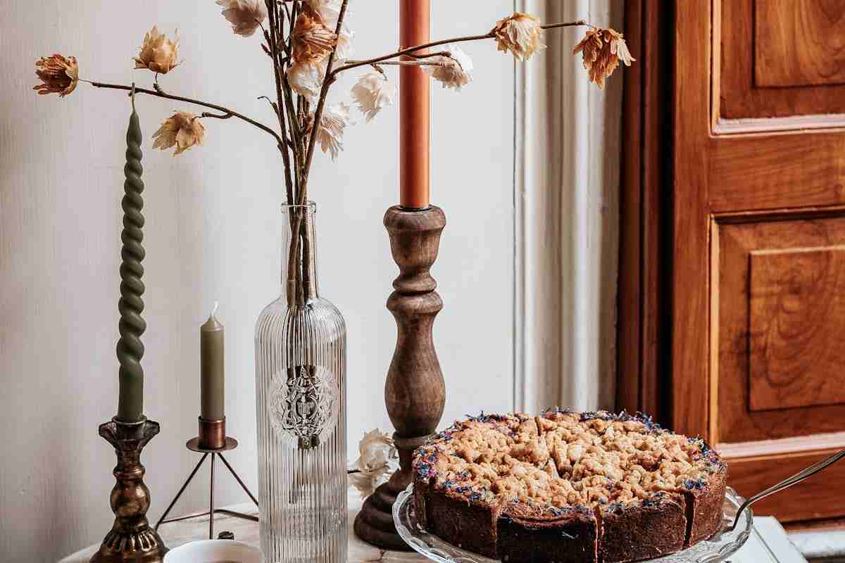 Tavolo con torta di mele, candele e fiori finti